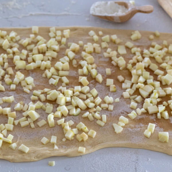 Rolled out dough with apple with sugar filling.