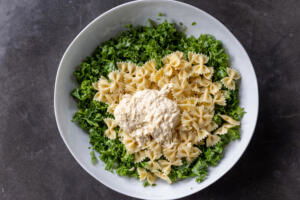 Kale, pasta and caesar dressing in a bowl.