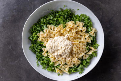 Kale, pasta and caesar dressing in a bowl.