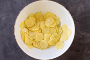Seasoned sliced potatoes in a bowl.