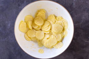 Parmesan added to sliced seasoned potatoes.
