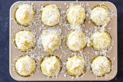 Potato Stacks topped with parmesan in a muffin pan.