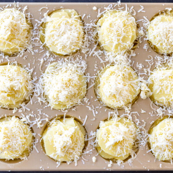 Potato Stacks topped with parmesan in a muffin pan.