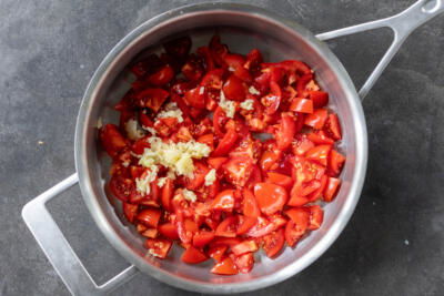 Cut up tomatoes with garlic in a pan.