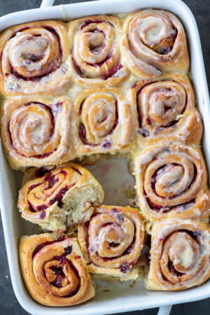 Cranberry Cinnamon Rolls with Orange Glaze in a baking pan.