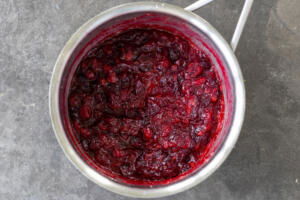 Cranberries cooked down with sugar in a pot.