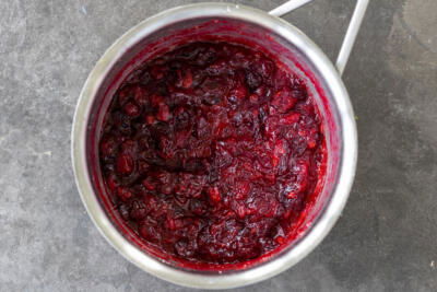 Cranberries cooked down with sugar in a pot.