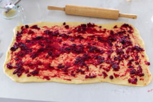 Rolled out dough with cranberry sauce.