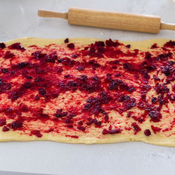 Rolled out dough with cranberry sauce.