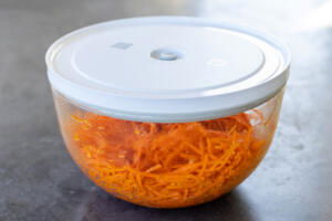 Korean Carrot Salad in a bowl with a cover.