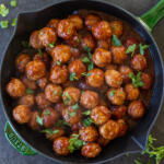 Cranberry Meatballs in a serving dish with herbs on top.