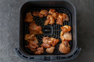 Raw chicken in air fryer basket.