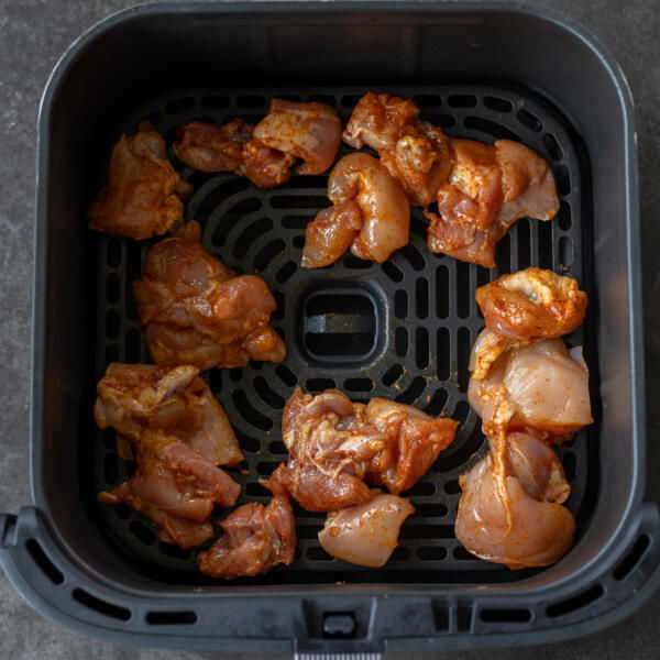 Raw chicken in air fryer basket.