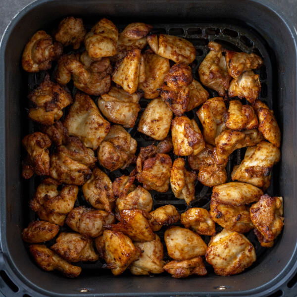 Air fryer basket with chicken.