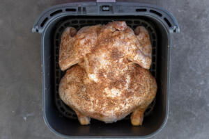 Chicken in an air fryer basket.