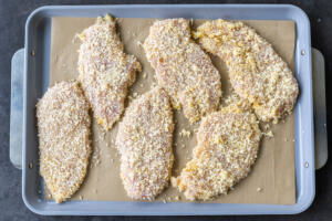 Coated chicken cutlets on a baking sheet.