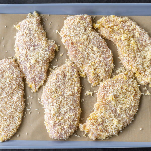 Baked Chicken Cutlets sprayed with oil on a baking sheet.