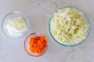 Cabbage, carrots and onion in bowls.