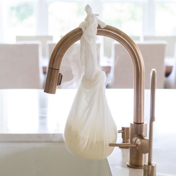 Cheese cloth with cheese over a sink.