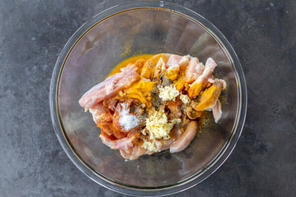 Chicken with seasoning in a bowl.