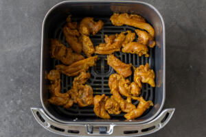 Chicken in an air fryer basket.
