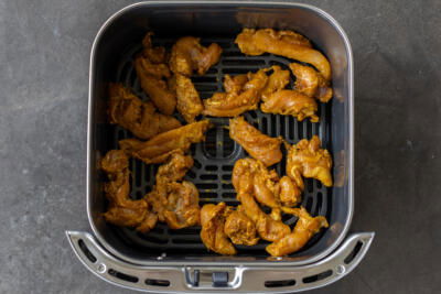 Chicken in an air fryer basket.