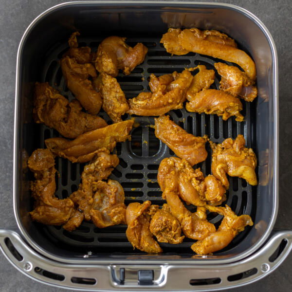 Chicken in an air fryer basket.