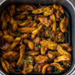 Chicken in an air fryer basket.