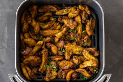 Chicken in an air fryer basket.