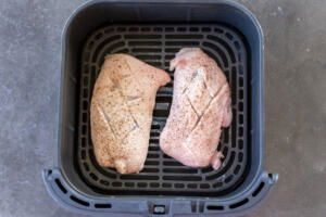 Air fryer basket with duck breast.