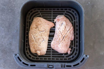 Air fryer basket with duck breast.