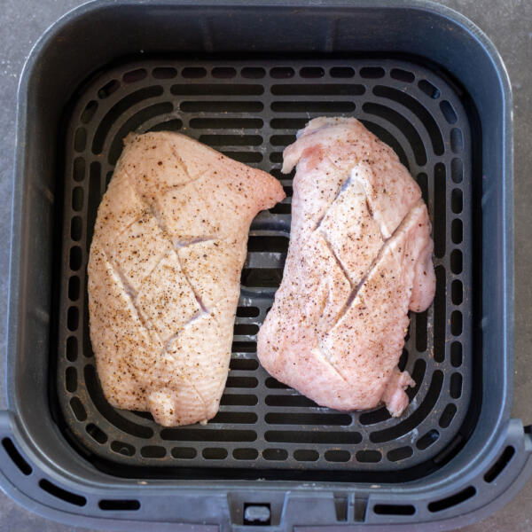 Air fryer basket with duck breast.