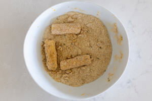Cheese sticks coated in crumbs in a bowl.