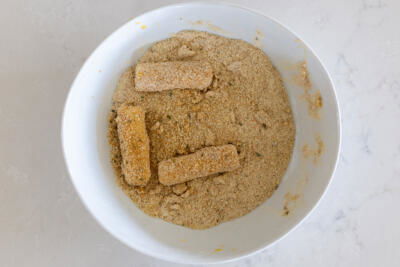 Cheese sticks coated in crumbs in a bowl.