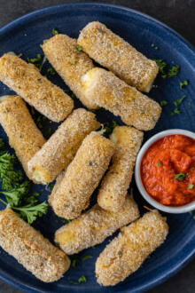 Air Fryer Mozzarella Sticks on a plate with sauce.