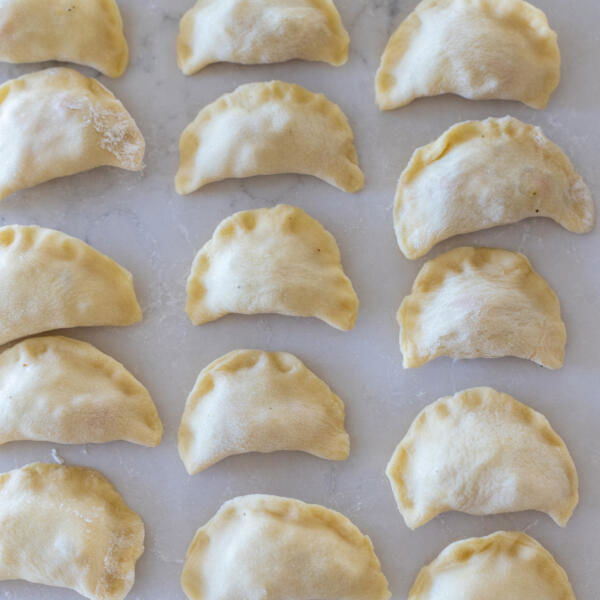 pinched closed varenyky on a floured surface.