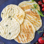 Baked Cottage Cheese Flatbread on a tray with herbs.