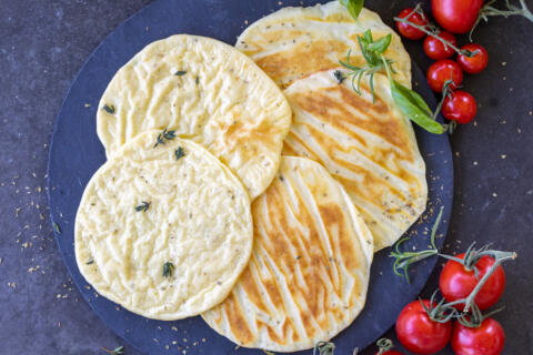 Baked Cottage Cheese Flatbread on a tray with herbs.