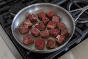 Seasoned steak in a pan.