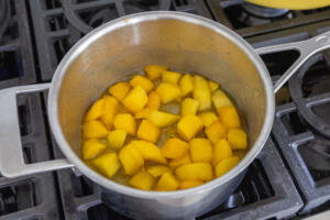 Mango in a pan with lemon juice and sugar.
