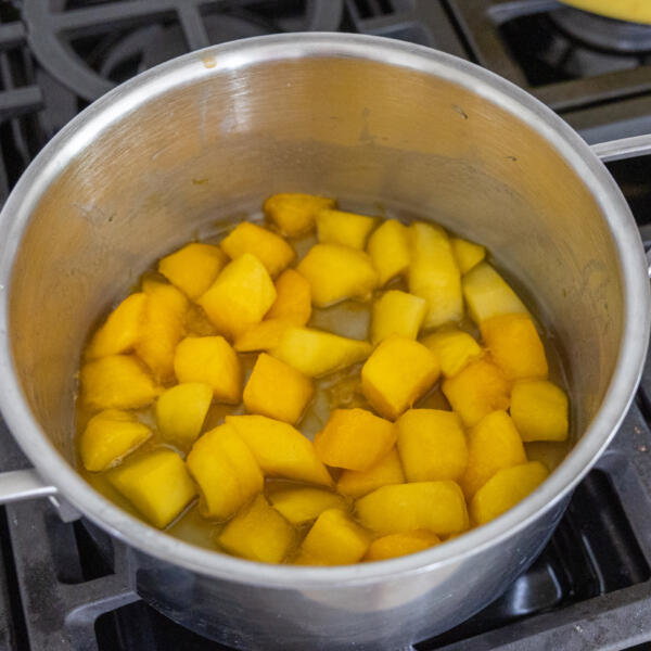 Mango in a pan with lemon juice and sugar.