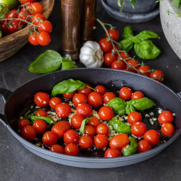 Cherry tomatoes, garlic, oil and basil in a pan.