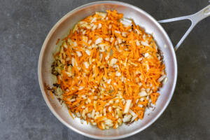 Onion and carrots cooking in a pan.