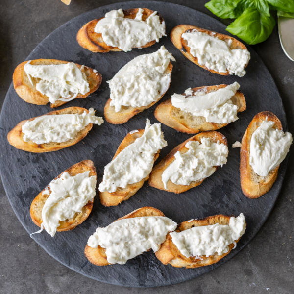 Toasted bread with burrata on a tray.
