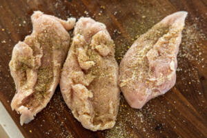 Seasoned chicken on a cutting board.