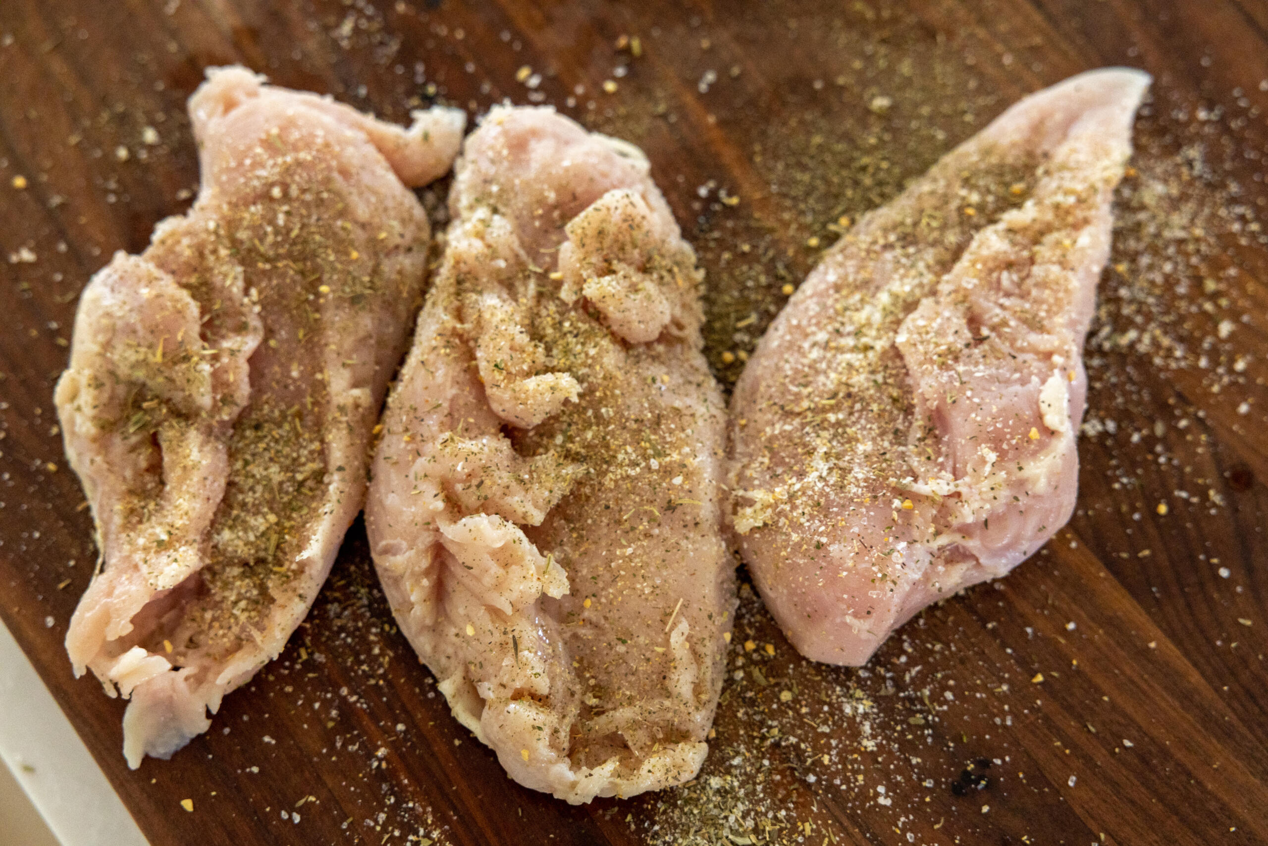 Seasoned chicken on a cutting board.