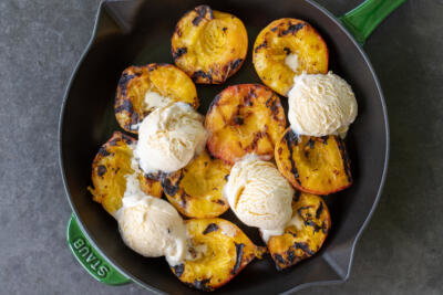 Grilled peaches with ice cream in a tray.