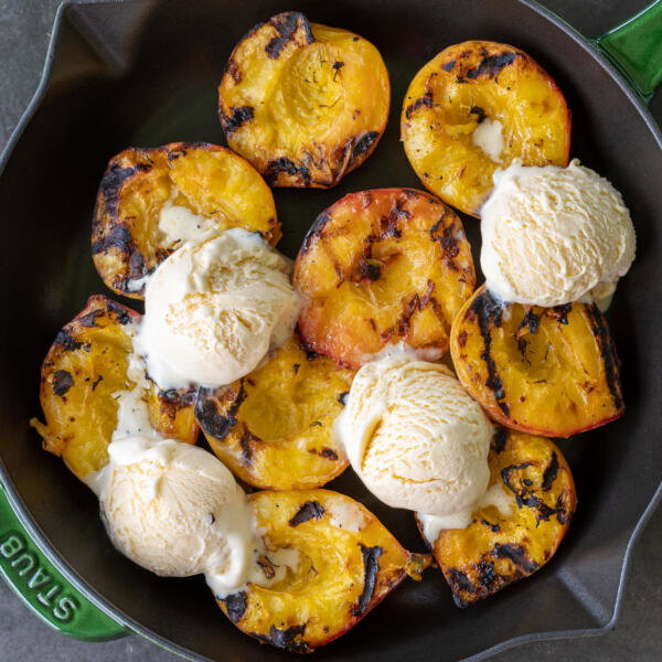 Grilled peaches with ice cream in a tray.