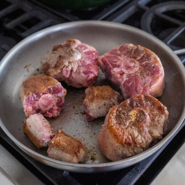 Oxtail getting browned in a pan.
