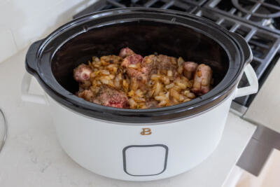 Oxtail and onion in a slow cooker with seasoning.